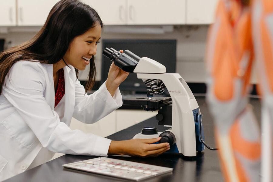 Student looks into a microscope in a laboratory session.